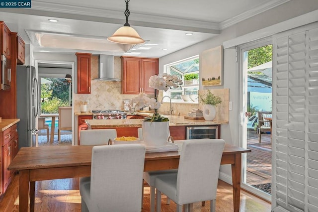 dining room with wine cooler, sink, crown molding, and light hardwood / wood-style floors