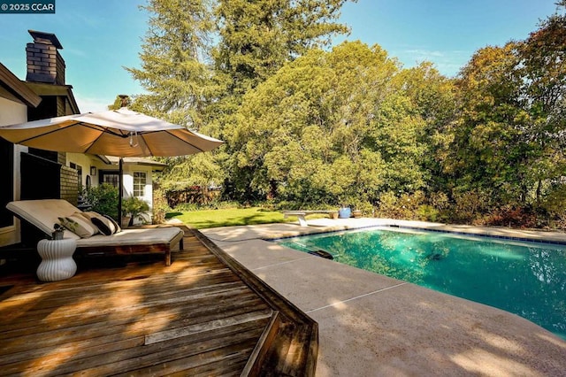 view of swimming pool with a wooden deck and a diving board