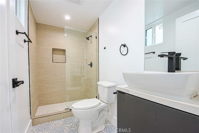 bathroom featuring tiled shower, vanity, toilet, and tile patterned flooring