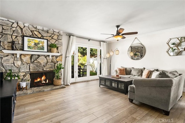 living room with ceiling fan, a fireplace, and light wood-type flooring