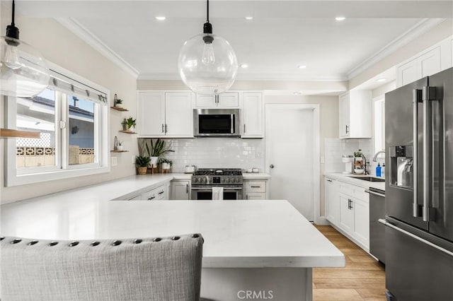 kitchen with white cabinetry, stainless steel appliances, sink, and hanging light fixtures