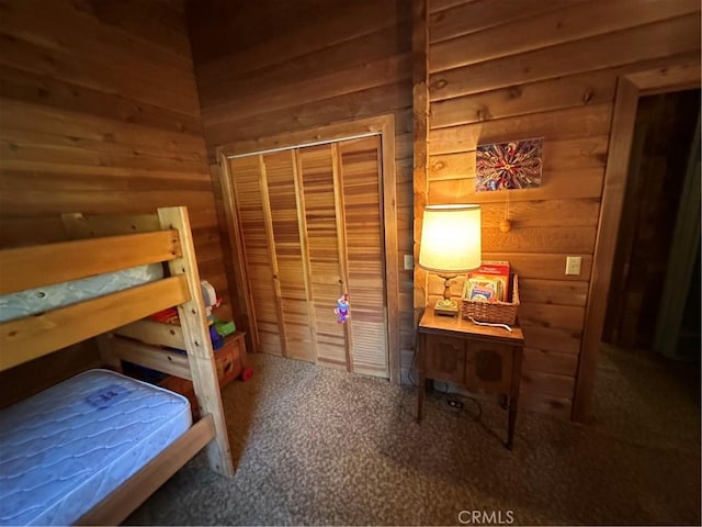 bedroom with carpet floors, a closet, and wood walls