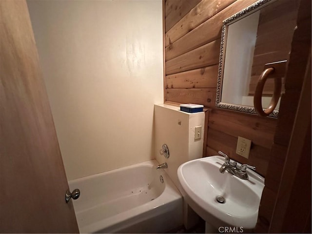 bathroom featuring sink, bathtub / shower combination, and wood walls