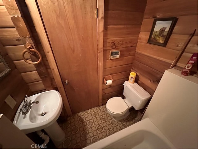 bathroom with sink, wooden walls, and toilet