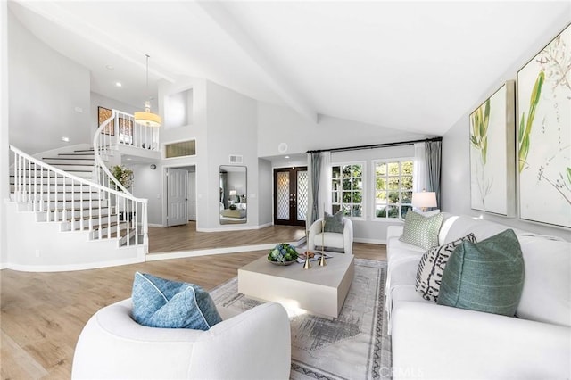 living room with wood-type flooring, high vaulted ceiling, and french doors