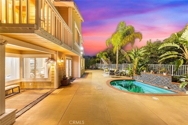 pool at dusk with a patio area