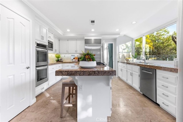 kitchen with white cabinetry, built in appliances, a breakfast bar area, and a kitchen island