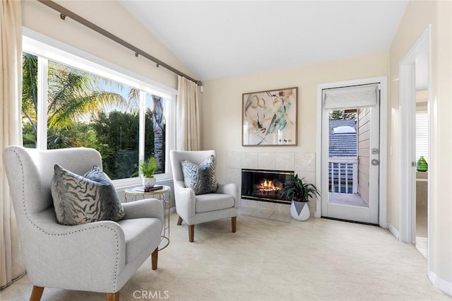 sitting room with light colored carpet, a tiled fireplace, and vaulted ceiling