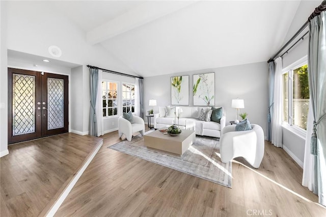 living room featuring a wealth of natural light, french doors, beamed ceiling, and light wood-type flooring