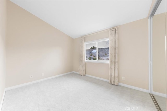 carpeted empty room with lofted ceiling