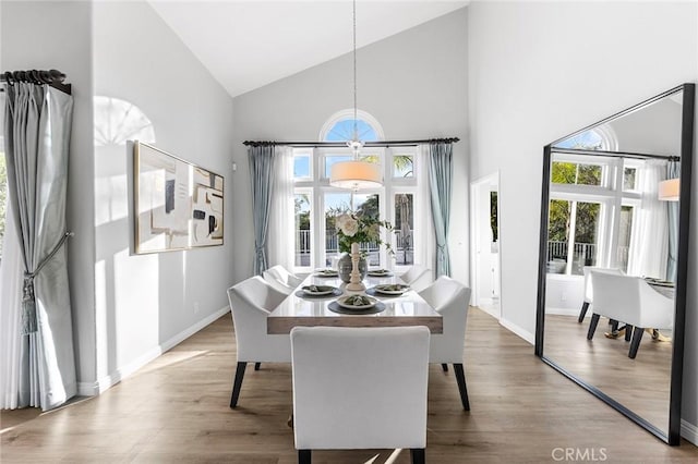 dining room with wood-type flooring, plenty of natural light, and high vaulted ceiling