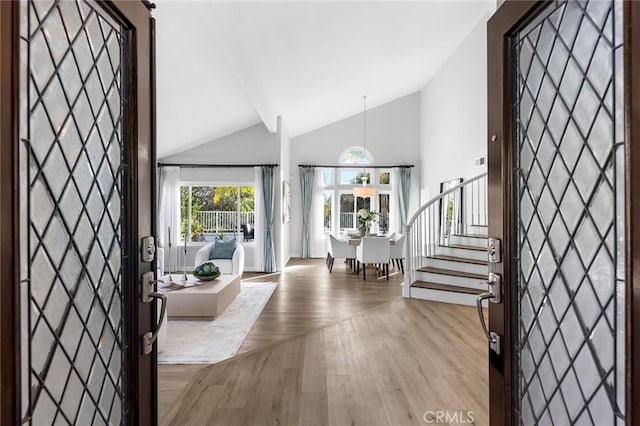 foyer entrance with light hardwood / wood-style flooring and high vaulted ceiling