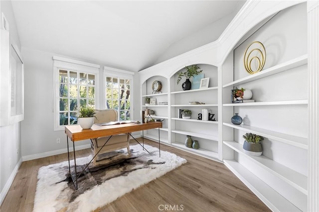 office area featuring lofted ceiling, hardwood / wood-style floors, and built in shelves