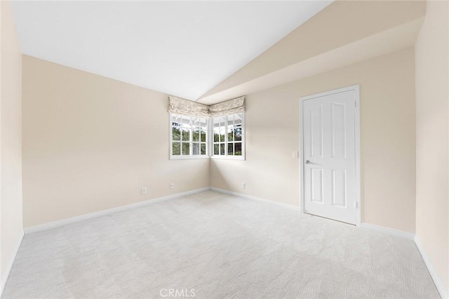 spare room featuring lofted ceiling and light colored carpet