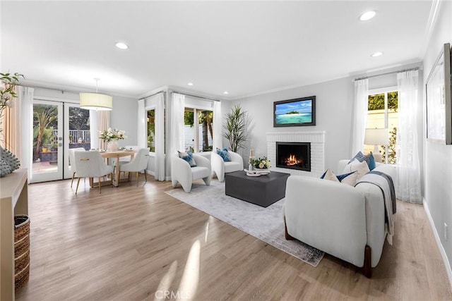 living room featuring ornamental molding, a brick fireplace, and light hardwood / wood-style floors