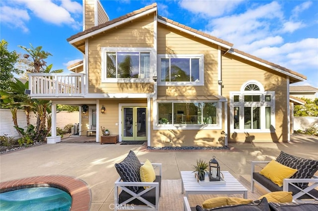 rear view of property with an outdoor living space, a patio area, french doors, and a balcony