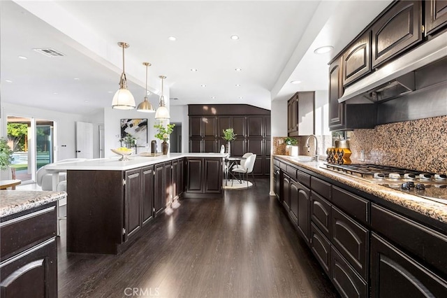 kitchen with dark hardwood / wood-style floors, a center island, pendant lighting, and dark brown cabinetry