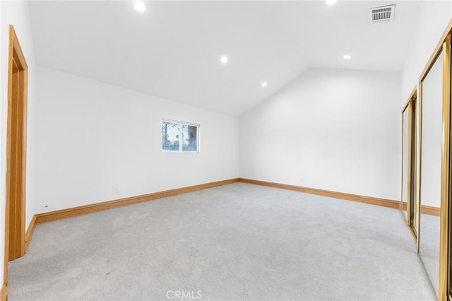 unfurnished bedroom featuring vaulted ceiling, light colored carpet, and a closet