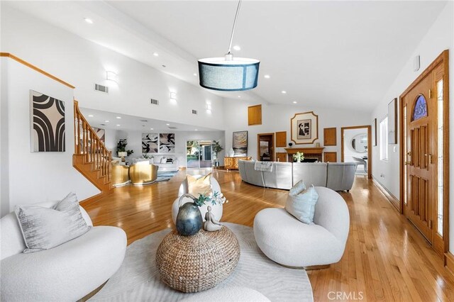 living room with high vaulted ceiling and light hardwood / wood-style floors