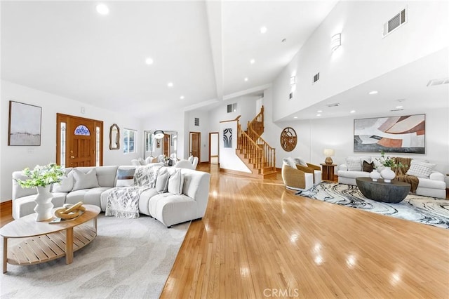 living room with beamed ceiling, high vaulted ceiling, and light hardwood / wood-style flooring