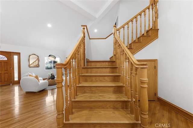 stairs featuring hardwood / wood-style floors and high vaulted ceiling