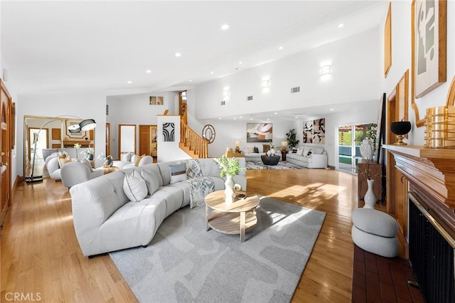 living room with a towering ceiling and light wood-type flooring