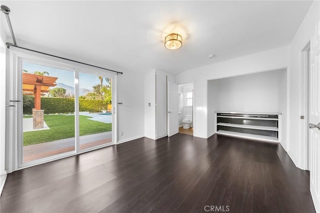 unfurnished bedroom featuring dark hardwood / wood-style flooring, ensuite bath, and access to outside