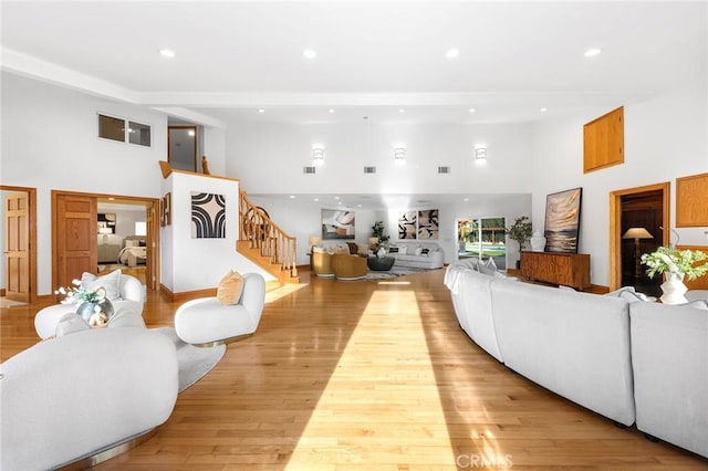 living room featuring a towering ceiling and light hardwood / wood-style flooring