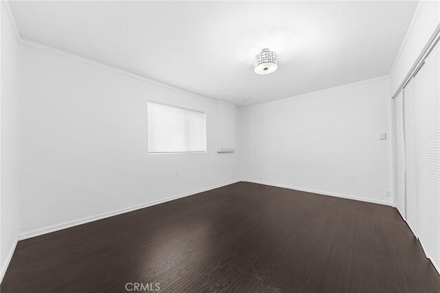 spare room featuring crown molding and dark wood-type flooring