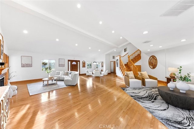 living room featuring vaulted ceiling with beams and light hardwood / wood-style flooring