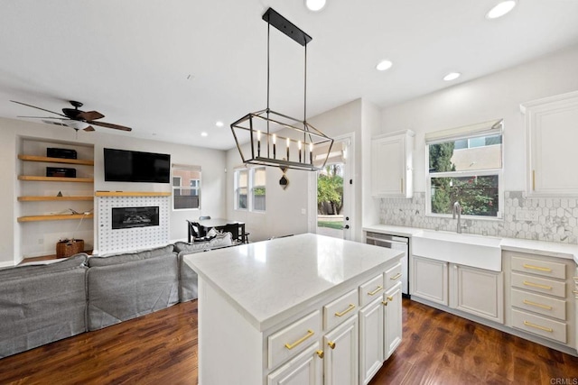 kitchen with hanging light fixtures, white cabinetry, a kitchen island, and sink