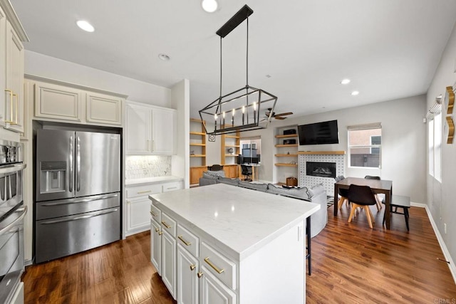 kitchen featuring tasteful backsplash, a center island, pendant lighting, stainless steel appliances, and a fireplace