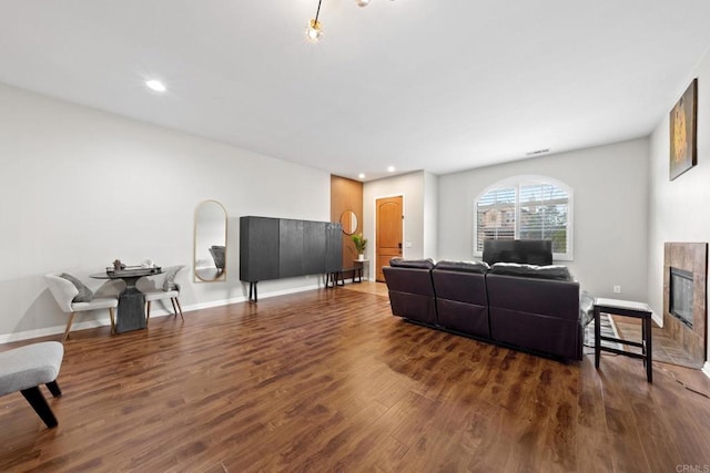 living room with a tiled fireplace and dark hardwood / wood-style floors