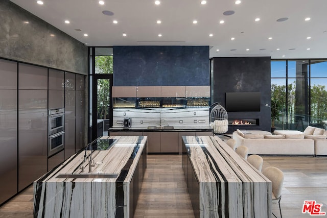 kitchen featuring a large island, double oven, light hardwood / wood-style flooring, and a large fireplace