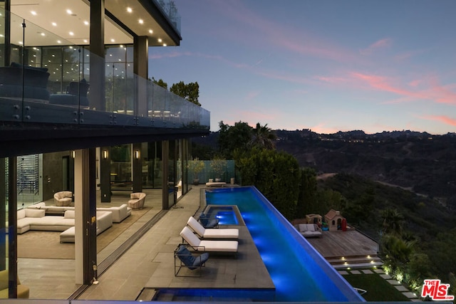 pool at dusk featuring outdoor lounge area