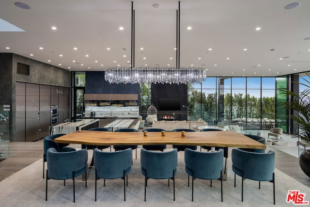 kitchen featuring a breakfast bar, light wood-type flooring, a wall of windows, a large island, and oven