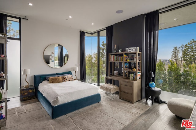 bedroom featuring multiple windows, a wall of windows, and light hardwood / wood-style flooring