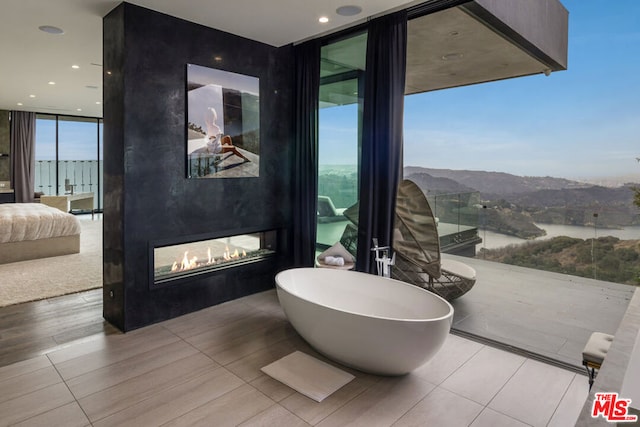 bathroom featuring expansive windows, tile patterned flooring, and a water and mountain view