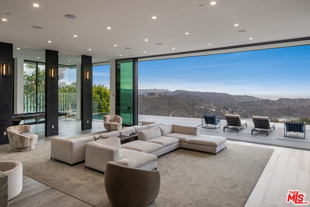 living room featuring a mountain view, light wood-type flooring, and a wall of windows