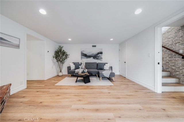 living room with brick wall and light hardwood / wood-style floors