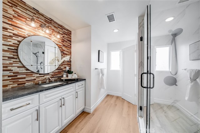 bathroom with vanity, decorative backsplash, a shower with shower door, and wood-type flooring