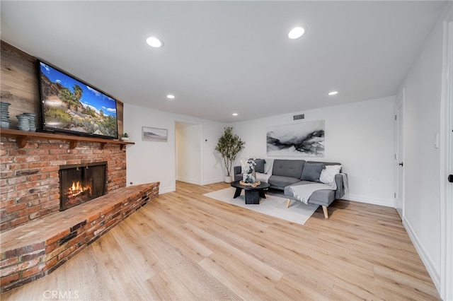 living room featuring a brick fireplace and light hardwood / wood-style floors