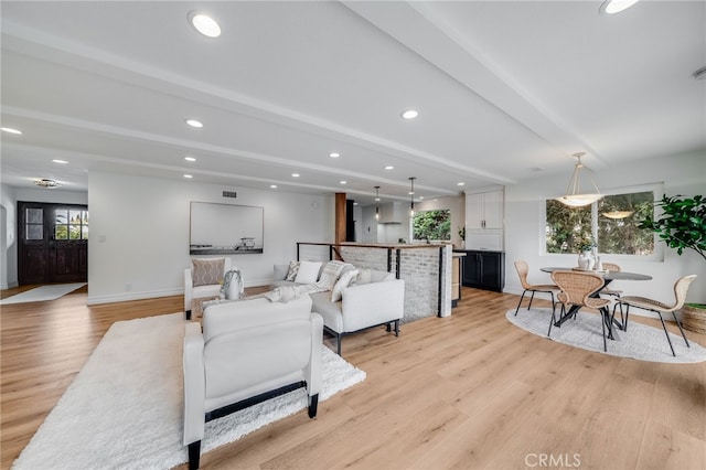 living room featuring a wealth of natural light, beam ceiling, and light hardwood / wood-style flooring