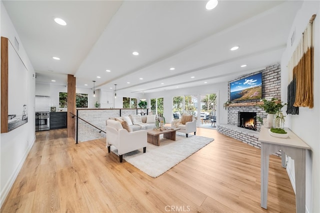 living room featuring a brick fireplace, beam ceiling, and light hardwood / wood-style flooring