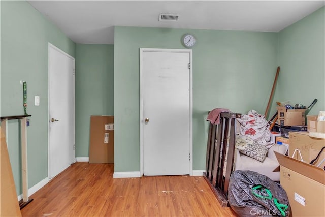 bedroom featuring light wood finished floors, visible vents, and baseboards