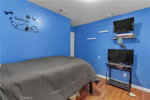 bedroom with visible vents, baseboards, and wood finished floors