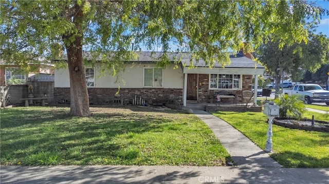 view of front of home featuring a front yard, brick siding, and stucco siding