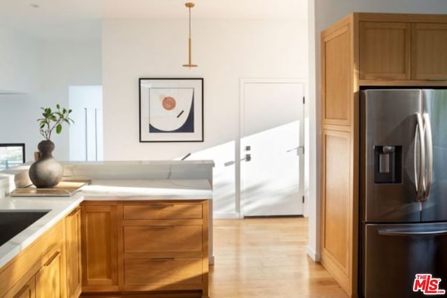 kitchen featuring hanging light fixtures, stainless steel refrigerator with ice dispenser, and light wood-type flooring