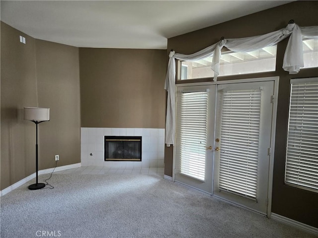 unfurnished living room with light carpet, plenty of natural light, and a tile fireplace