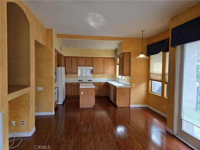 kitchen with white appliances, dark hardwood / wood-style floors, decorative backsplash, a kitchen island, and decorative light fixtures